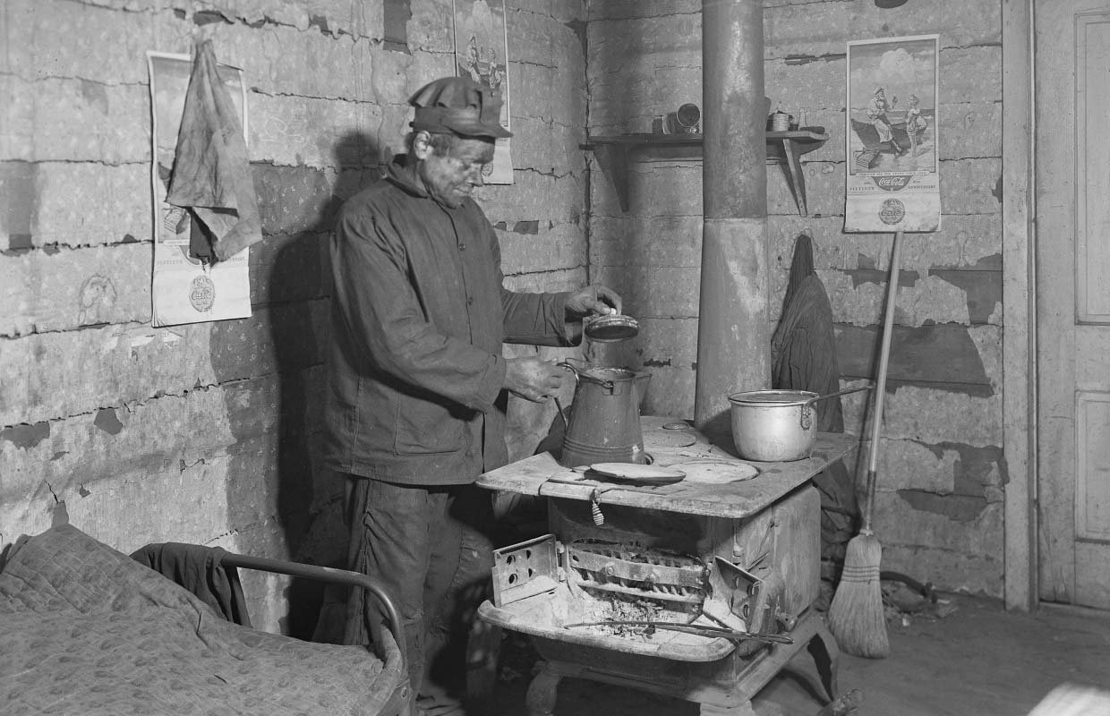 Coal miner preparing a pot of tea inside a workers hut