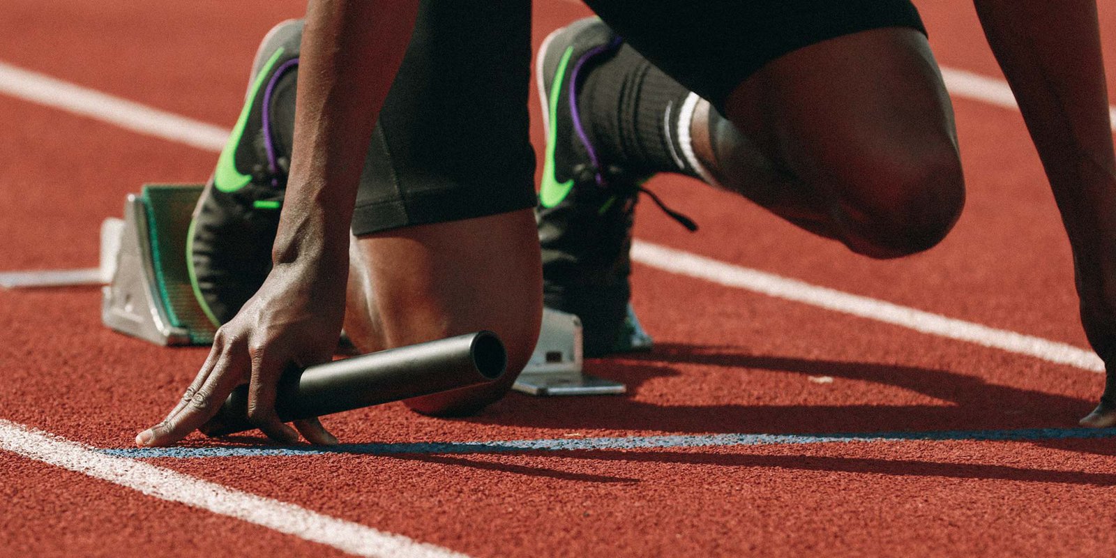Sprinter crouching at the starting line of an athletics track