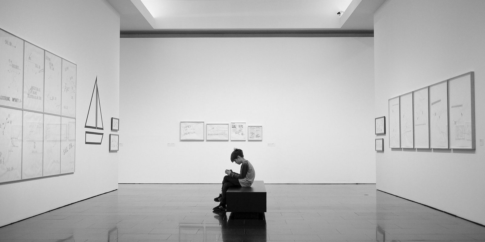 Young boy seated inside an art gallery and using a mobile device