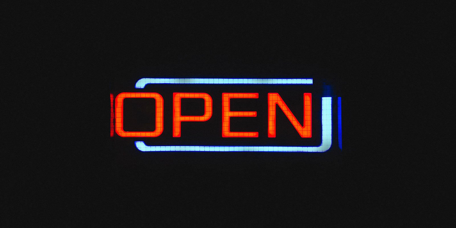 Illuminated neon sign of the word 'open' on a dark background